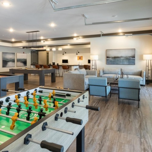 a clubroom with a foosball table, chairs and tables