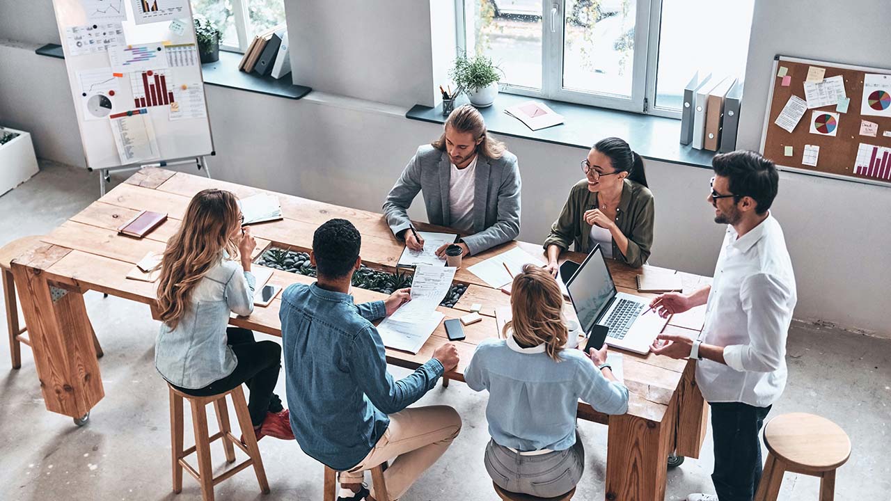 Coworkers working together at a large table in an office.